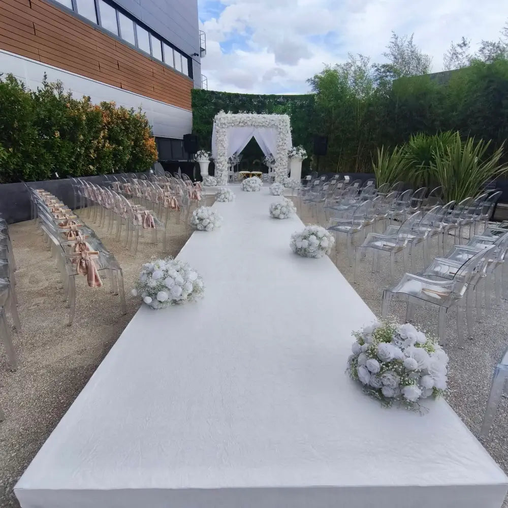 Location podium cérémonie mariage en plein air — estrade blanche avec arche florale et chaises Ghost transparentes, Paris Île-de-France